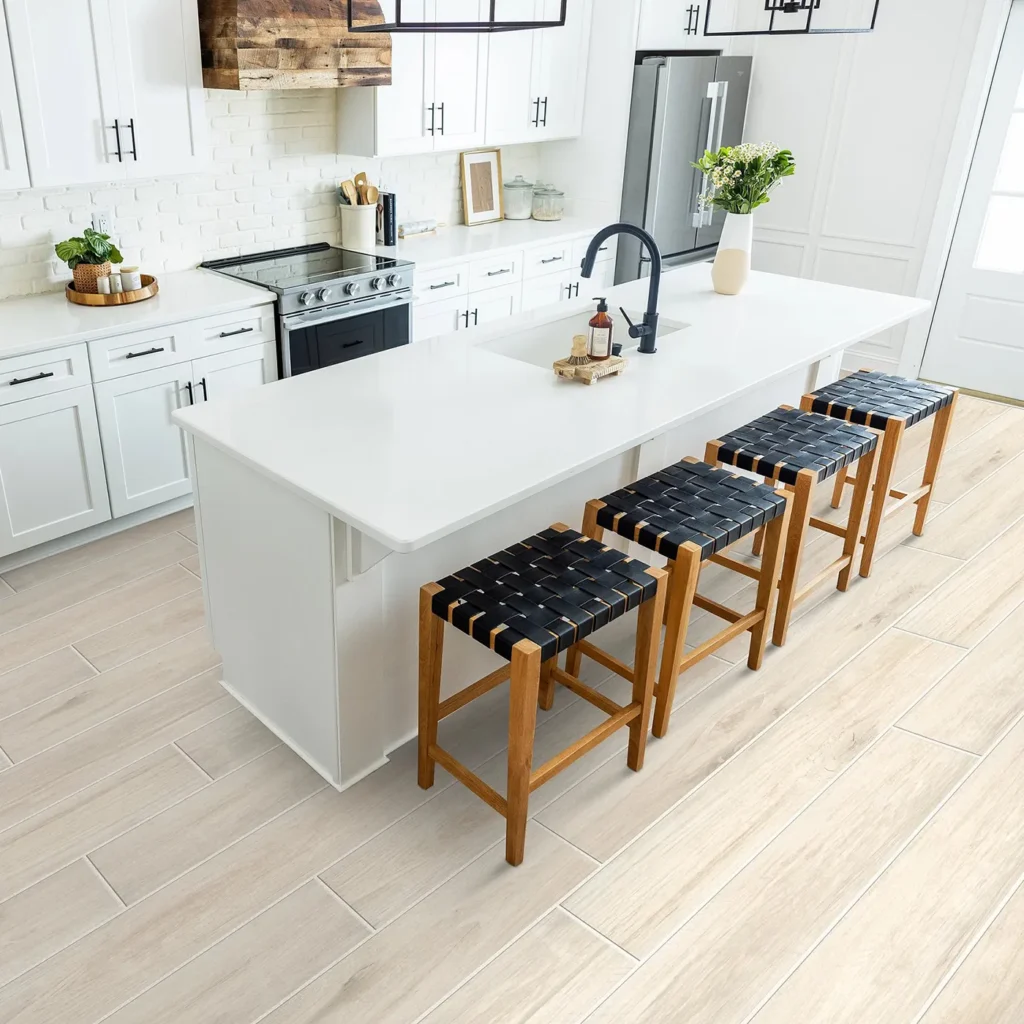 Overhead view of white kitchen island with woven bar stools on light wood-look Shaw Floors Savannah tile flooring