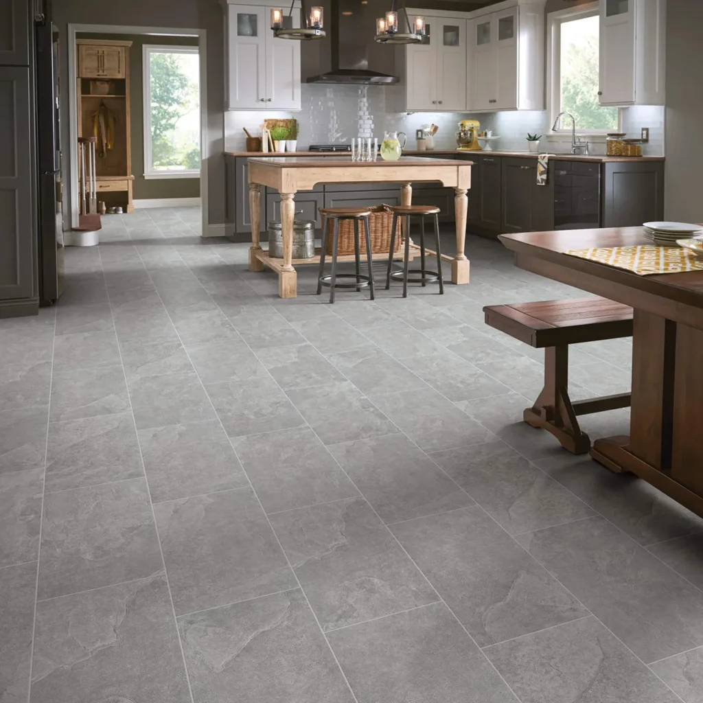 Kitchen with wood island and dining table on large gray stone-look Shaw Floors Crown Smoke tile flooring