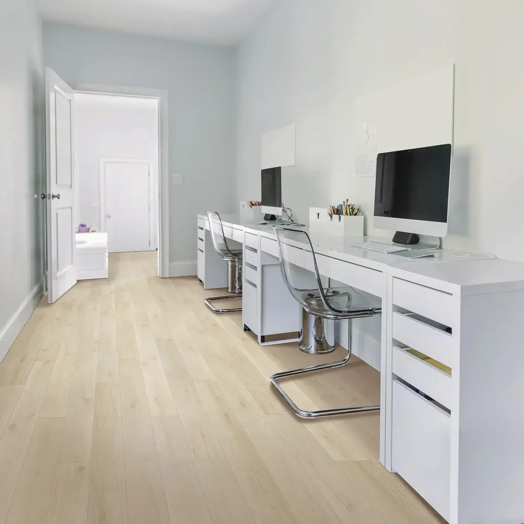 Bright home office with long white desk, monitors and acrylic chairs on pale blonde Mohawk RevWood Plus Bellente laminate flooring
