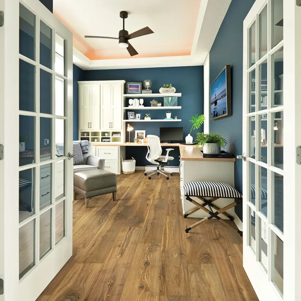Home office seen through French doors with built-in desk and ceiling fan on rustic brown Mohawk RevWood Premier Morena Bluffs laminate flooring