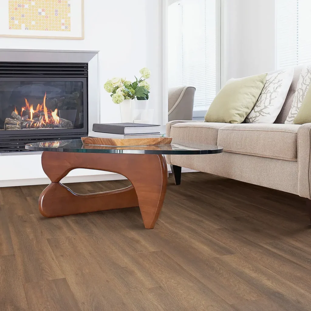 Living room with fireplace, glass coffee table and beige sofa on medium brown Mohawk RevWood Premier Miramar Shores laminate flooring
