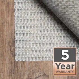 Gray webbed rug pad folded under an area rug on wood flooring with 5 Year Warranty badge
