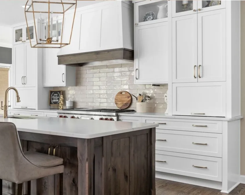 Bright kitchen featuring white cabinetry, subway tile backsplash, and a dark wood island.