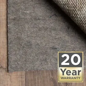 Gray felt rug pad under an area rug on wood flooring with 20 Year Warranty badge