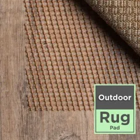 Brown waffle-grip outdoor rug pad under a woven rug on wood decking with Outdoor Rug Pad badge