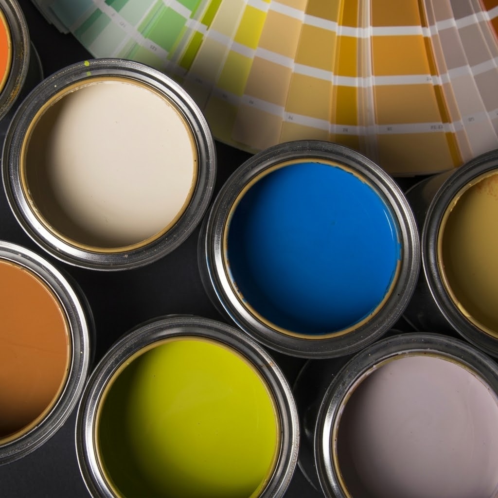 Open cans of colorful paint beside a paint color fan deck